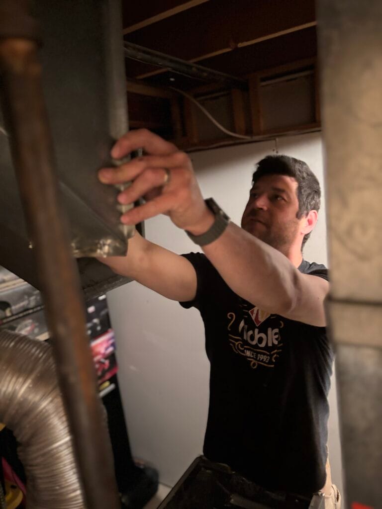 HVAC Zack technician installing a high-efficiency furnace plenum in an Oshawa basement.