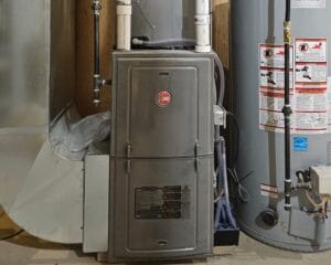 Older gas furnace with PVC venting and water heater beside it, serviced by HVAC Zack in a Durham Region basement.