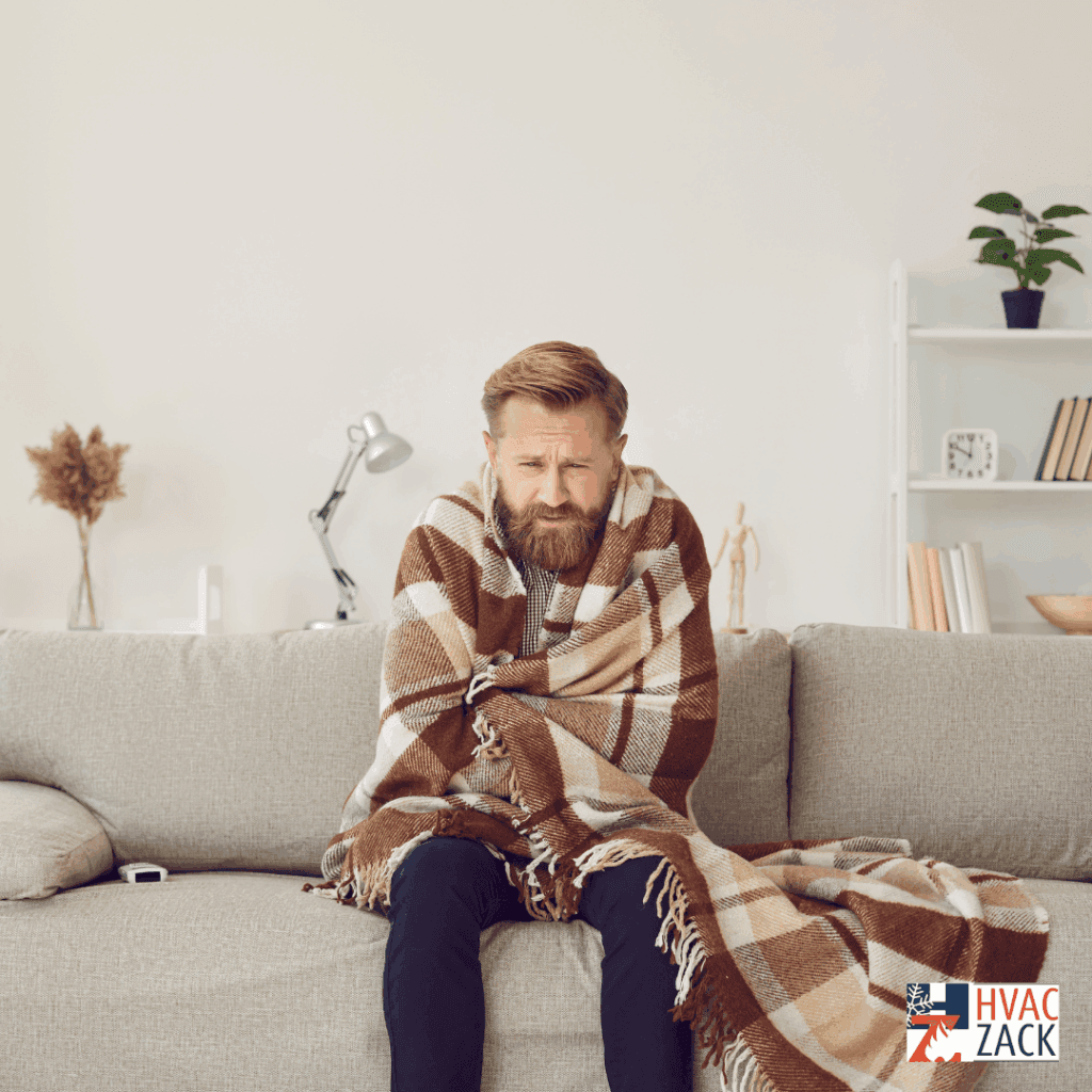 Cold homeowner wrapped in a blanket on a sofa, illustrating a no-heat furnace situation in Durham Region.