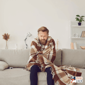 Cold homeowner wrapped in a blanket on a sofa, illustrating a no-heat furnace situation in Durham Region.