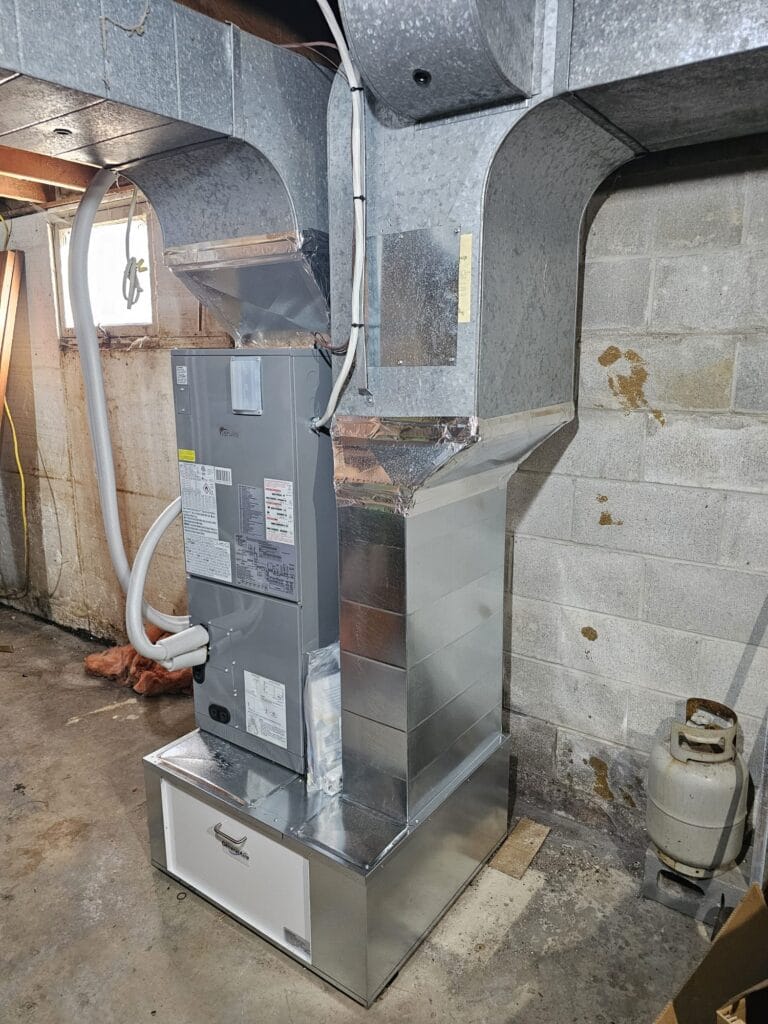 New central air handler and duct transitions installed where an old oil furnace stood in a Colborne basement.