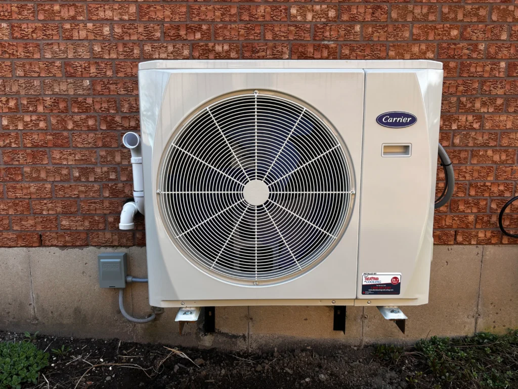 Carrier air conditioner outdoor unit installed against brick wall at a Durham Region home