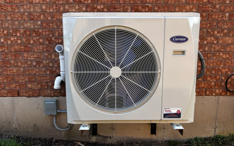 Carrier air conditioner outdoor unit installed against brick wall at a Durham Region home